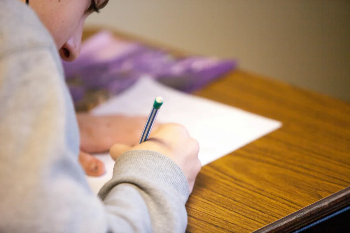Student writing an exam paper during retake preparation